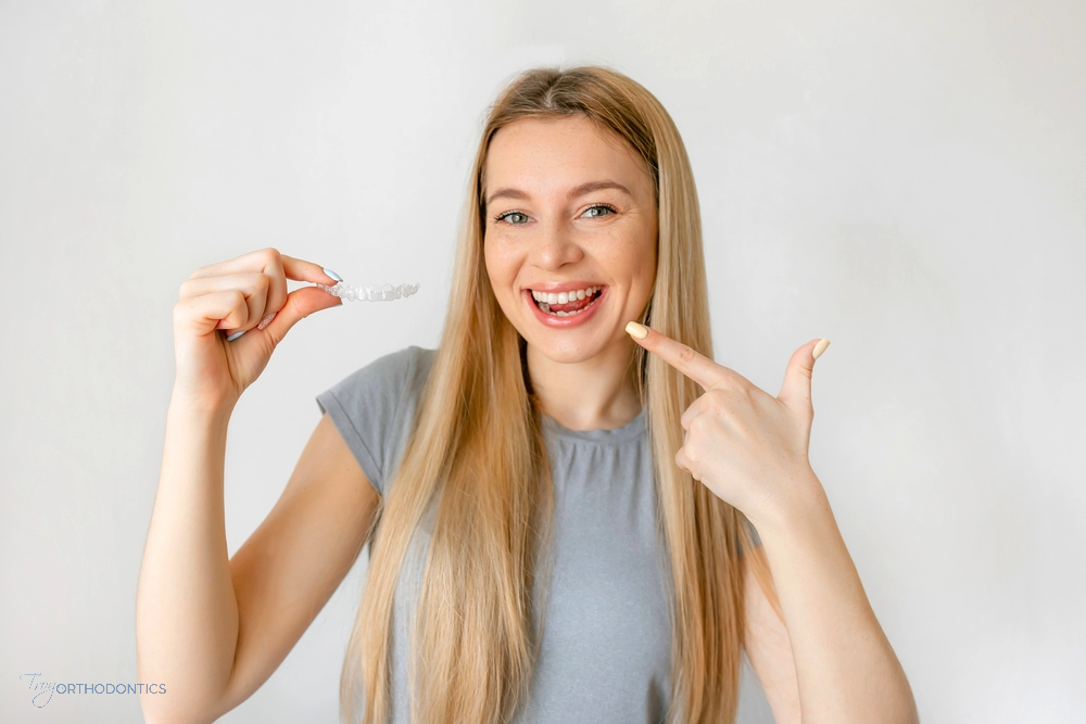 Teenage girl demonstrating how to use a clear aligner—an effective method on how to fix overbite in Little Falls, NJ.